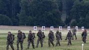 Grupa żołnierzy w mundurach na poligonie, w tle tarcze strzeleckie i drzewa.