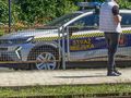 Na zdjęciu widoczny jest samochód straży miejskiej oraz stojący mężczyzna.
