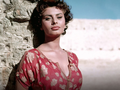 Sophia Loren. Na zdjęciu kobieta o ciemnych włosach w koronkowej bluzce, stojąca przy kamiennej ścianie.