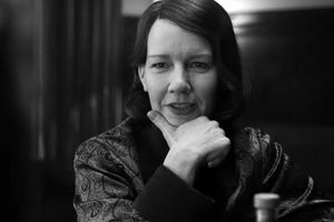 Kobieta w ciemnej odzieży, z ręką pod brodą, myśli w eleganckim wnętrzu. monochromatyczna.