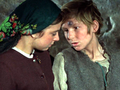 Dwoje dzieci w starych ubraniach, rozmawiają w kamiennej scenerii. Chłopiec ma brudną twarz.
