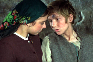 Dwoje dzieci w starych ubraniach, rozmawiają w kamiennej scenerii. Chłopiec ma brudną twarz.