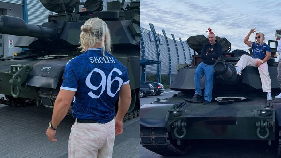 Skolim i jego przyjaciele stoją na czołgu, obok pojazdu widać budynki i zaparkowane samochody.