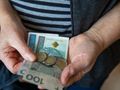 Zdjęcie przedstawia ręce osoby trzymającej banknoty i monety.