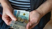 Zdjęcie przedstawia ręce osoby trzymającej banknoty i monety.