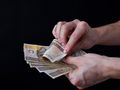 Zdjęcie rąk trzymających polskie banknoty na czarnym tle.