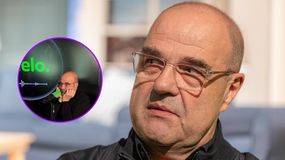 Cezary Żak w czarnej bluzie, słucha rozmowy w podcaście. Ujęcie twarzy i mikrofonu.