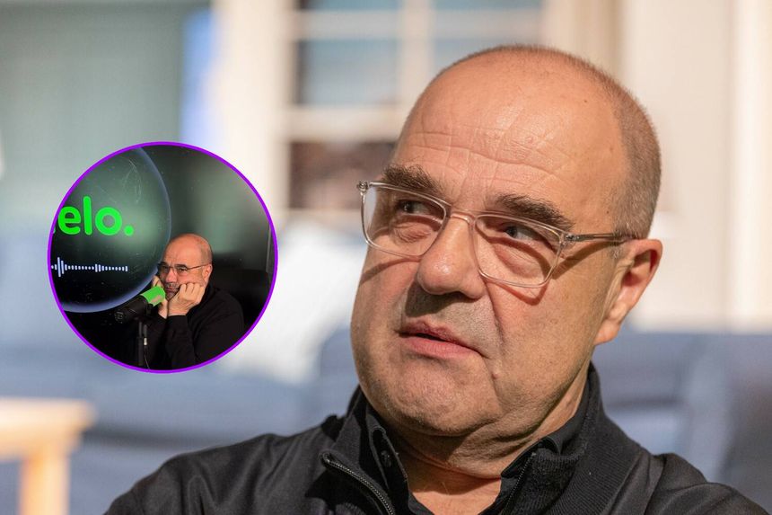 Cezary Żak w czarnej bluzie, słucha rozmowy w podcaście. Ujęcie twarzy i mikrofonu.
