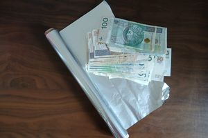 Na stole leży gotówka, folia spożywcza oraz srebrna folia.