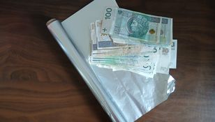 Na stole leży gotówka, folia spożywcza oraz srebrna folia.