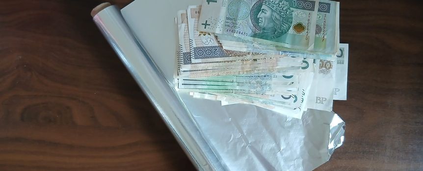 Na stole leży gotówka, folia spożywcza oraz srebrna folia.
