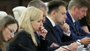 Izba dyskusyjna, sześć osób w garniturach, skupionych nad dokumentami. Kobieta z blond włosami na pierwszym planie.