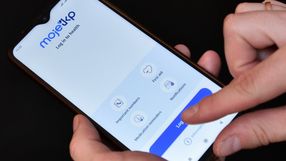 Zdjęcie przedstawia osobę trzymającą telefon z aplikacją Moje 3KP, na ekranie widoczny przycisk logowania.