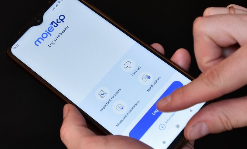 Zdjęcie przedstawia osobę trzymającą telefon z aplikacją Moje 3KP, na ekranie widoczny przycisk logowania.