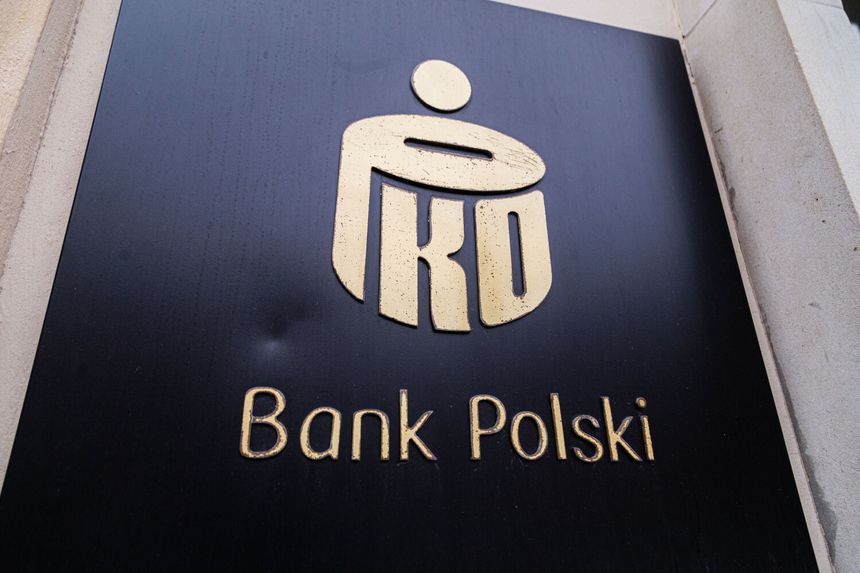 Logo banku PKO Bank Polski na czarnym tle. Złote litery i symbol bankowy.
