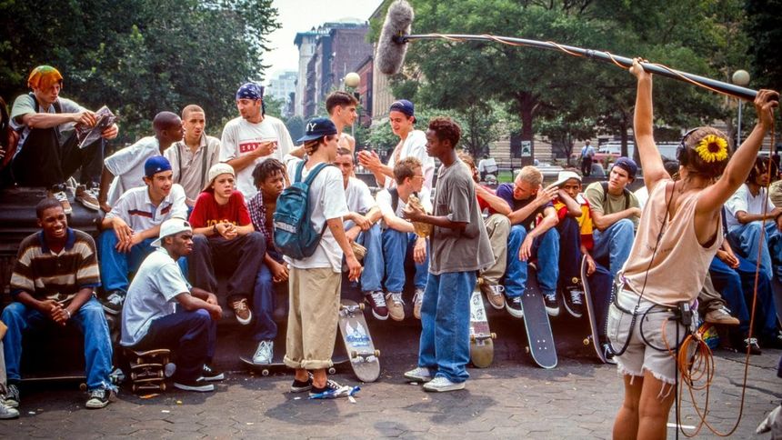 Grupa młodych ludzi w skateparku, rozmawiających i uczących się skateboardingu.