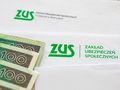 Zdjęcie: banknoty i koperty z logo ZUS oraz napisem 