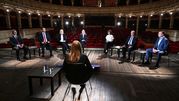 Dyskusja polityczna w teatrze, siedem osób w eleganckich ubraniach, widownia pusta.