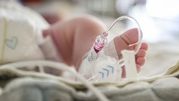 Zdjęcie małego, okrytego stopy z wkłuciem dożylnym w szpitalnym otoczeniu.