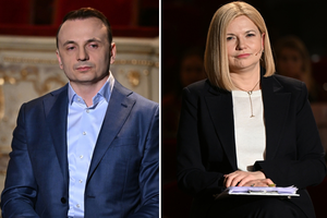 Dwoje ludzi w eleganckich strojach siedzi obok siebie, w tle widać zarys sceny.