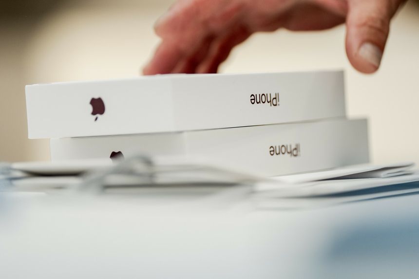 Na zdjęciu widoczne są dwa opakowania iPhone'ów oraz ręka, która dotyka jednego z nich.