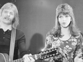 Dwoje artystów na scenie; mężczyzna z gitarą i kobieta śpiewająca. Czarno-biała fotografia.