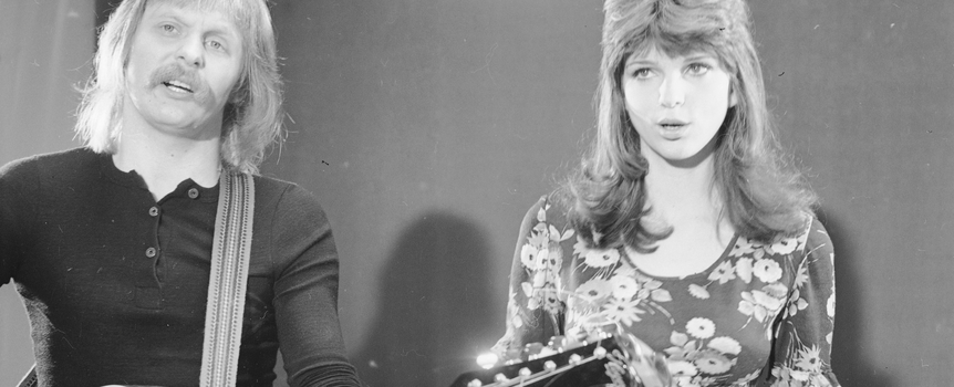 Dwoje artystów na scenie; mężczyzna z gitarą i kobieta śpiewająca. Czarno-biała fotografia.