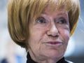Kobieta z krótkimi, złotymi włosami, w czarnej bluzce, z zamyśloną miną.