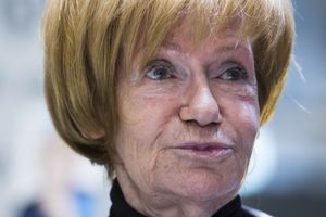 Kobieta z krótkimi, złotymi włosami, w czarnej bluzce, z zamyśloną miną.