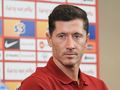 Na zdjęciu Robert Lewandowski w czerwonej koszulce, z włosami w ciemnym kolorze, wygląda poważnie.