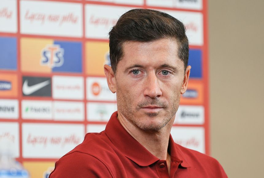Na zdjęciu Robert Lewandowski w czerwonej koszulce, z włosami w ciemnym kolorze, wygląda poważnie.