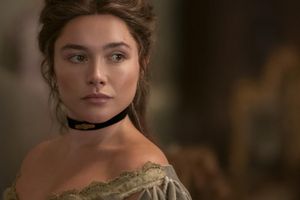 Na zdjęciu widoczna młoda kobieta z brązowymi włosami, ubrana w elegancką suknię z dekoltem.