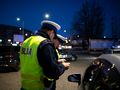 Dwa policjanty w żółtych kamizelkach kontrolują kierowcę przy samochodzie nocą.