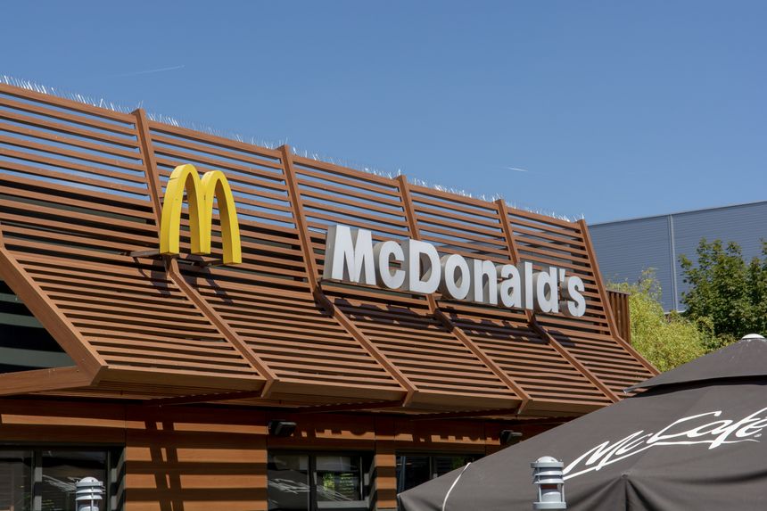 Restauracja McDonald's z logo nad wejściem, słoneczny dzień, drewniana fasada.