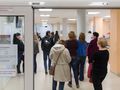 Opis ALT: Długi korytarz przychodni, kolejka pacjentów czekających na wizytę.