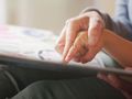 Opis ALT: Dwie dłonie, większa i mniejsza, dotykają wspólnie kartki książki.