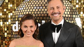 Krzysztof Ibisz i Paulina Sykut-Jeżyna uśmiechają się na tle lustrzanej ściany.