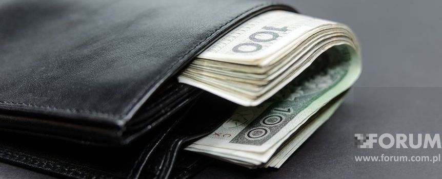 Czarny portfel z widocznymi banknotami, leżący na szarym tle.
