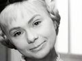 Kobieta z jasnymi włosami i uśmiechem, w czarno-białym zdjęciu.