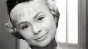 Kobieta z jasnymi włosami i uśmiechem, w czarno-białym zdjęciu.