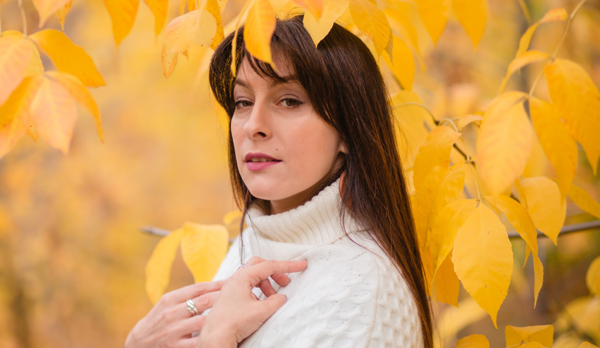 Brunetka w białym swetrze wśród żółtych jesiennych liści