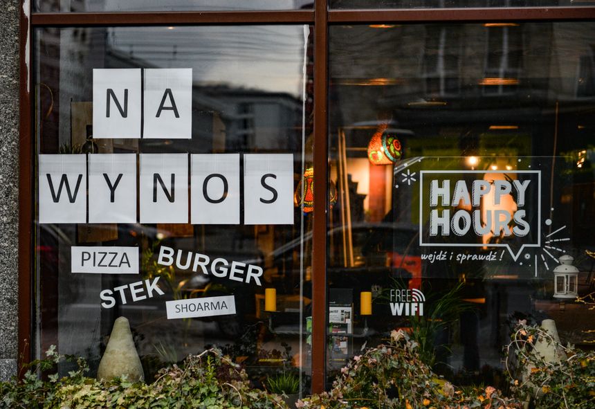 Witryna restauracji z napisami „NA WYNOS”, „PIZZA”, „BURGER”, „STEK”, „SHOARMA”.