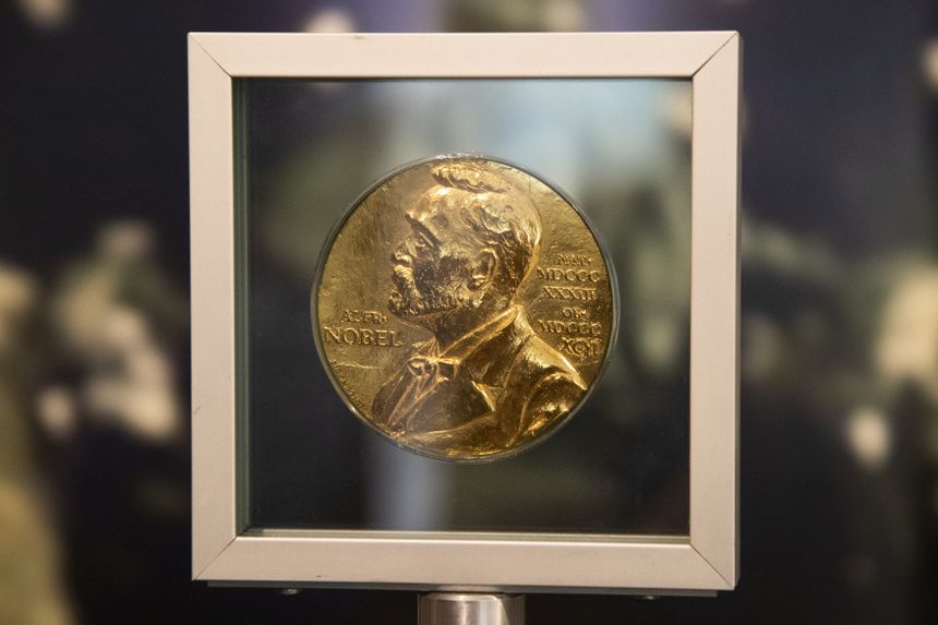 Złoty medal Nobla w oznakowanej gablotce, z wizerunkiem Alfreda Nobla.
