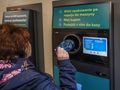 Osoba wrzucająca plastikową butelkę do automatu do zwrotu opakowań. Informacje o procesie na ekranie.