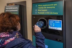 Osoba wrzucająca plastikową butelkę do automatu do zwrotu opakowań. Informacje o procesie na ekranie.