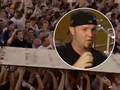 Limp Bizkit na Woodstocku 1999. Mężczyzna w czapce mówi do mikrofonu, w tle tłum unoszący ręce z kawałkiem drewna.