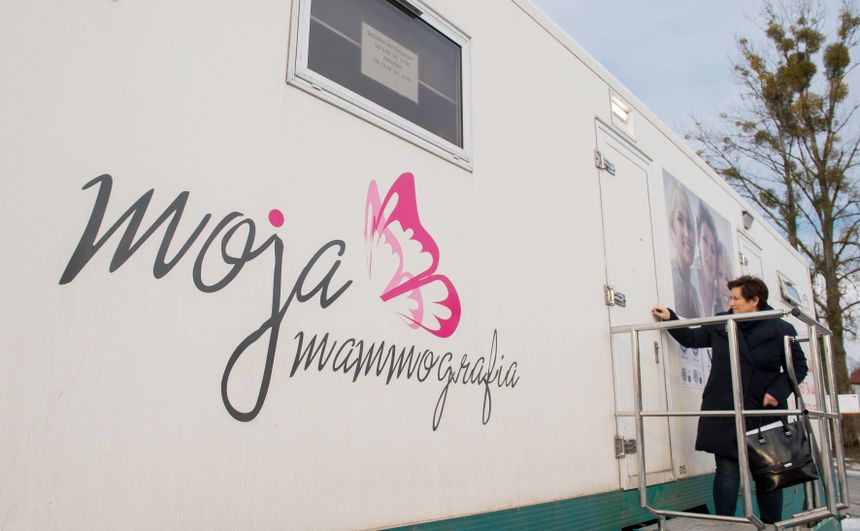 Kobieta podchodzi do mobilnej pracowni mammograficznej z napisem „moja mammografia”.