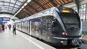 Pociąg Leo Express na stacji, przy peronie z pasażerem i dużymi oknami.