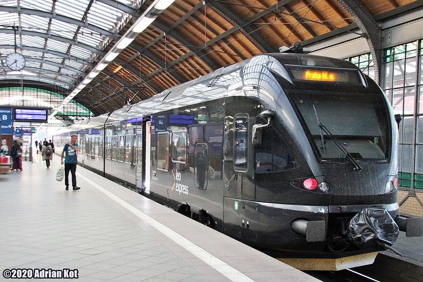 Pociąg Leo Express na stacji, przy peronie z pasażerem i dużymi oknami.