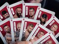 Zbiór kart z wizerunkami zawodników walk FAME MMA, trzymanych w dłoni. Kolory: czerwony i szary.